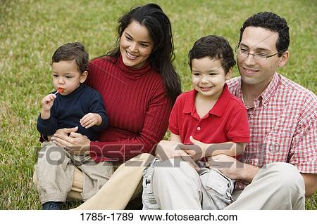 Stock Photo - Hispanic family sitting on grass. Fotosearch