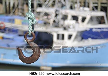 Stock Image - Hook hanging in front of boats at harbor, Hall's Harbour, Nova Scotia, Canada. Fotosearch