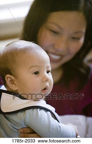 Stock Image - Infant boy being held by his mother. Fotosearch