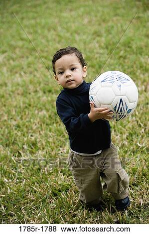Little boy standing on lawn with a soccer ball View Large Photo Image Stock Photo - Little boy standing on lawn with a soccer ball. Fotosearch