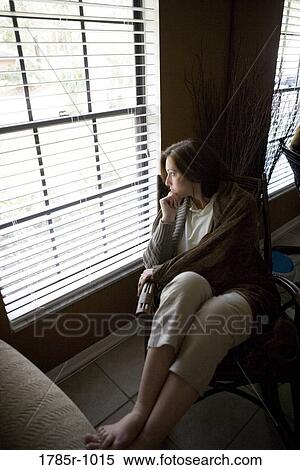 Lonely young woman staring out window View Large Photo Image Stock Photography - Lonely young woman staring out window. Fotosearch