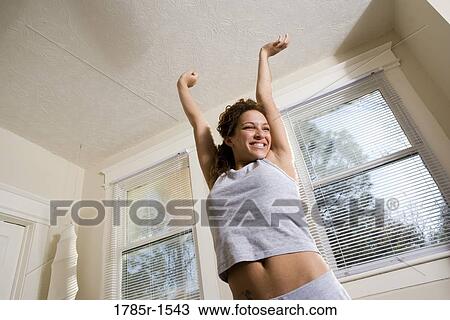 Low angle view of a happy and smiling young woman stretching View Large Photo Image Stock Image - Low angle view of a happy and smiling young woman stretching. Fotosearch