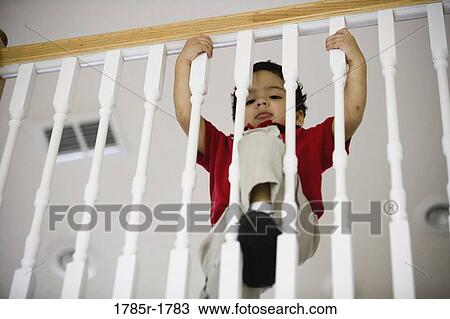 Low angle view of a little boy standing behind stair rails View Large Photo Image Stock Image - Low angle view of a little boy standing behind stair rails. Fotosearch