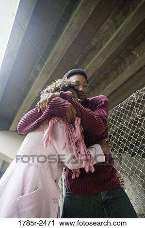 Low angle view of a young couple embracing View Large Photo Image Stock Image - Low angle view of a young couple embracing. Fotosearch