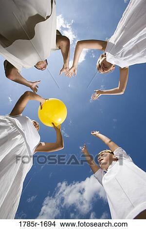 Picture - Low-angle view of family playing with a yellow ball. Fotosearch