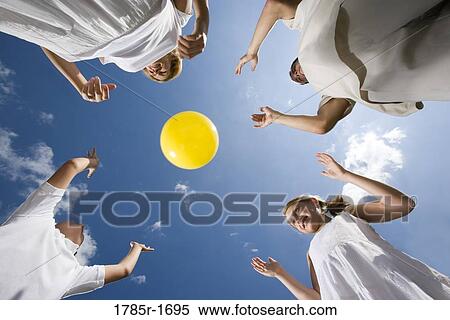 Low-angle view of family playing with a yellow ball View Large Photo Image Stock Photography - Low-angle view of family playing with a yellow ball. Fotosearch