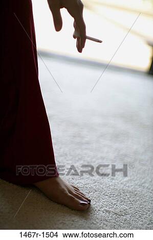 Picture - Low section view of a person holding a cigarette. Fotosearch