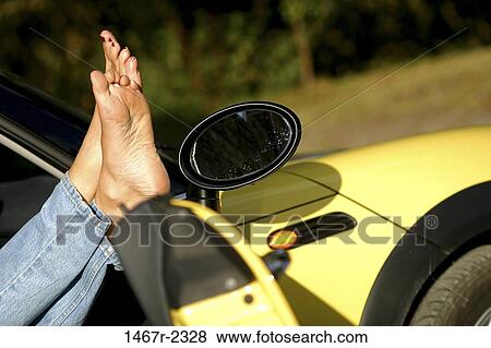 Stock Photo - Low section view of a person's feet on a car door. Fotosearch