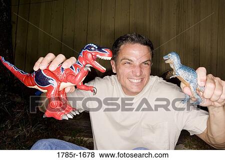 Stock Photo - Man playing with toy dinosaurs. Fotosearch