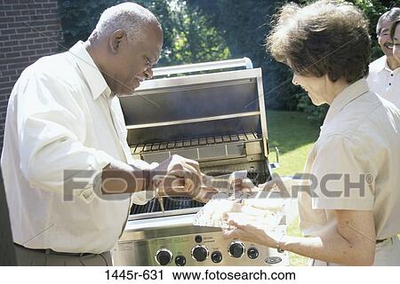 Man serving a woman food in front of a barbecue grill View Large Photo Image Stock Image - Man serving a woman food in front of a barbecue grill. Fotosearch