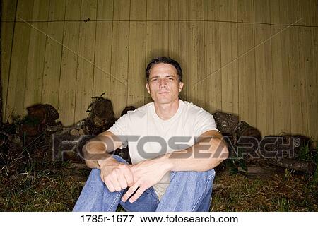 Man sitting by fence View Large Photo Image Stock Photo - Man sitting by fence. Fotosearch