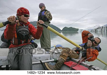 Picture - Man taking a picture of a young woman rafting in a lake, Alsek Lake, Alaska, USA. Fotosearch