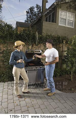 Mature couple drinking beer next to barbeque grill View Large Photo Image Stock Image - Mature couple drinking beer next to barbeque grill. Fotosearch