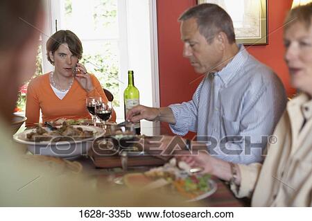 Mature couple sitting with their son and daughter at a dining table View Large Photo Image Stock Image - Mature couple sitting with their son and daughter at a dining table. Fotosearch