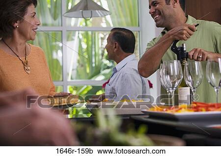 Stock Image - Mature man and a mature woman looking at each other with another mature man standing in the background. Fotosearch
