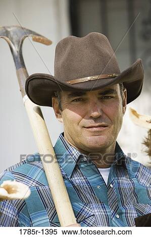 Stock Photography - Mature man wearing cowboy hat holding a shovel. Fotosearch