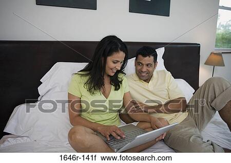 Mature woman using a laptop in the bed with a mature man reclining beside her View Large Photo Image Stock Image - Mature woman using a laptop in the bed with a mature man reclining beside her. Fotosearch