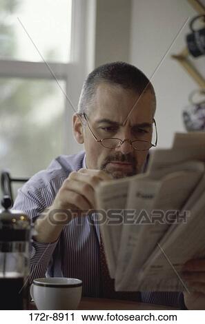 Stock Image - Mid adult man reading a newspaper. Fotosearch
