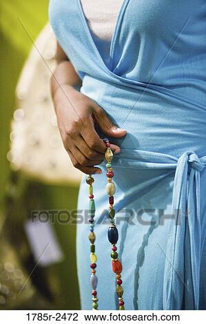 Stock Image - Midsection of a woman holding a necklace. Fotosearch
