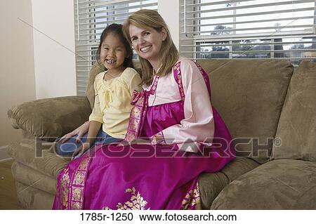 Stock Image - Mother and daughter in living room, mother wearing a Hanbok. Fotosearch