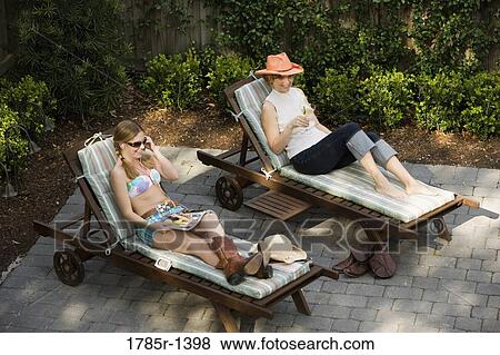 Stock Photo - Mother and daughter relaxing on deck chairs. Fotosearch