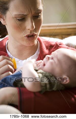 Mother holding and comforting her crying baby View Large Photo Image Stock Photo - Mother holding and comforting her crying baby. Fotosearch