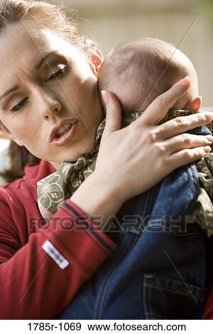 Mother holding and comforting her crying baby View Large Photo Image Stock Photo - Mother holding and comforting her crying baby. Fotosearch
