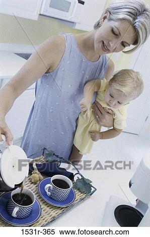 Mother holding her baby girl and pouring coffee into cups View Large Photo Image Stock Photography - Mother holding her baby girl and pouring coffee into cups. Fotosearch
