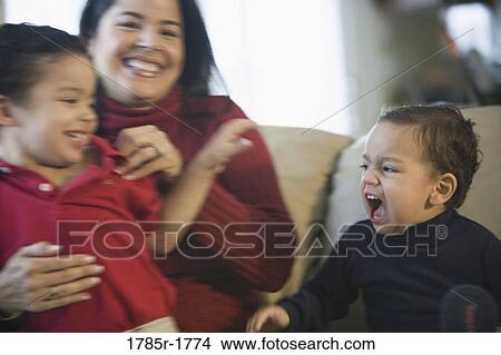 Picture - Mother sitting on a sofa with her sons. Fotosearch