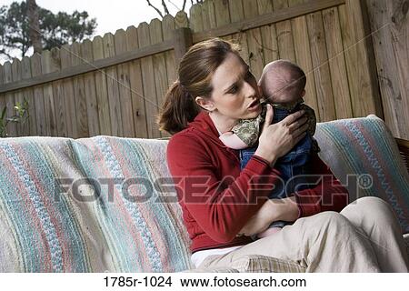 Mother sitting with baby by fence in backyard View Large Photo Image Picture - Mother sitting with baby by fence in backyard. Fotosearch