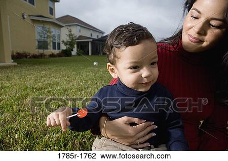 Stock Image - Mother sitting with her son on lawn. Fotosearch