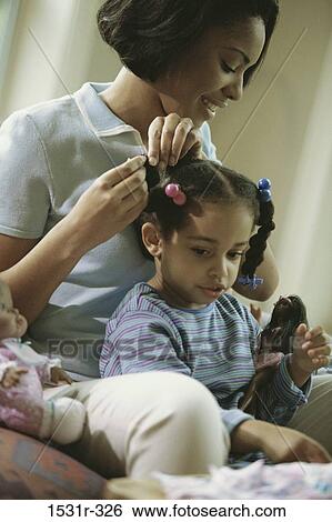 Stock Photograph - Mother styling her daughter's hair. Fotosearch