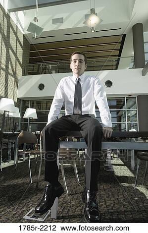 Office worker sitting on table View Large Photo Image Stock Image - Office worker sitting on table. Fotosearch