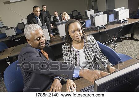 Older man helping younger business colleague in computer lab View Large Photo Image Stock Image - Older man helping younger business colleague in computer lab. Fotosearch