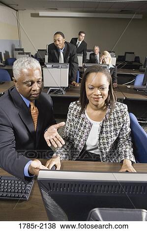 Older man helping younger business colleague in computer lab View Large Photo Image Stock Photo - Older man helping younger business colleague in computer lab. Fotosearch