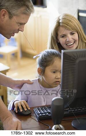 Parents and daughter looking at a computer View Large Photo Image Stock Image - Parents and daughter looking at a computer. Fotosearch