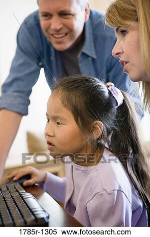 Parents and daughter looking at a computer View Large Photo Image Stock Photography - Parents and daughter looking at a computer. Fotosearch