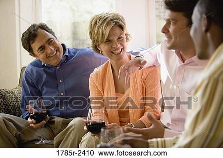 Stock Image - Parents chatting with adult son and friend. Fotosearch