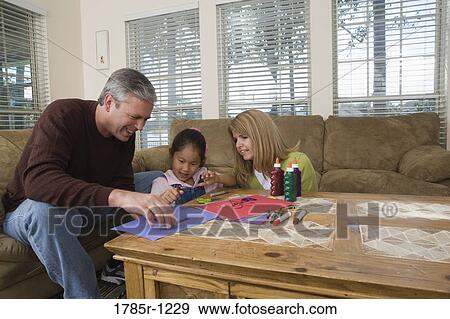 Stock Photo - Parents helping their daughter to draw. Fotosearch