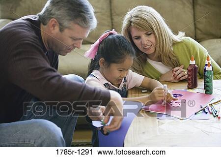 Parents helping their daughter with art work View Large Photo Image Stock Image - Parents helping their daughter with art work. Fotosearch