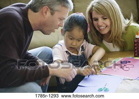Parents helping their daughter with art work View Large Photo Image Stock Image - Parents helping their daughter with art work. Fotosearch