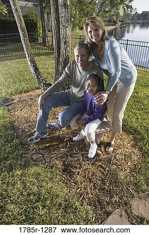 Stock Photo - Parents with daughter posing in backyard. Fotosearch
