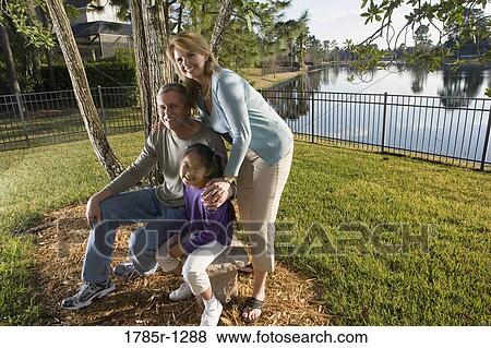 Stock Photo - Parents with daughter posing in backyard. Fotosearch