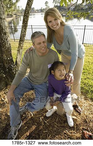 Stock Photo - Parents with daughter posing in backyard. Fotosearch