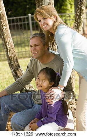Parents with daughter posing in backyard View Large Photo Image Stock Photograph - Parents with daughter posing in backyard. Fotosearch