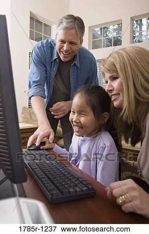 Parents with their daughter looking at a computer View Large Photo Image Stock Photo - Parents with their daughter looking at a computer. Fotosearch