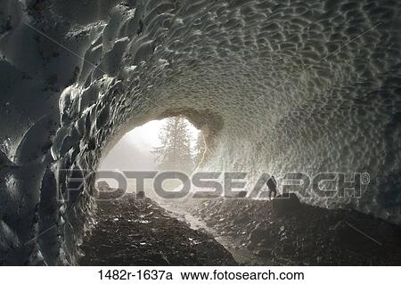 Stock Image - Person in an ice cave, Fiordland Recreation Area, Fiordland Conservancy, British Columbia, Canada. Fotosearch