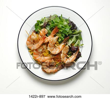 Stock Photo - Plate of grilled shrimp on skewers, yellow rice and salad. Fotosearch