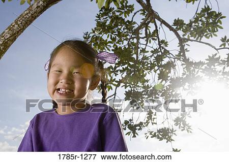 Portrait of a Asian girl sitting under a tree View Large Photo Image Stock Photo - Portrait of a Asian girl sitting under a tree. Fotosearch
