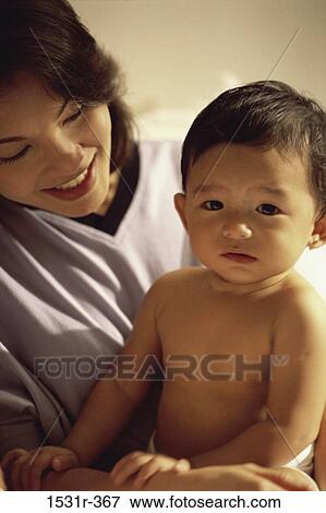 Stock Photo - Portrait of a baby boy sitting with his mother. Fotosearch